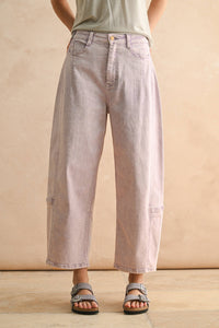 Person wearing light purple jeans and sandals on a beige background