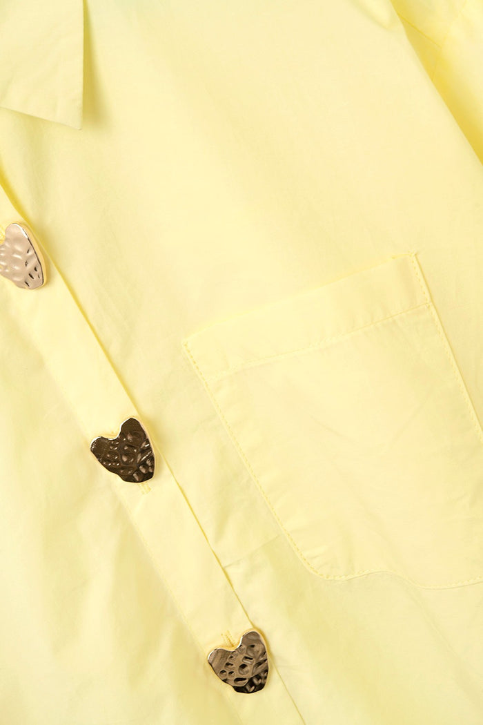 Close-up of a yellow fabric top with heart-shaped buttons.