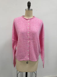 pale pink button-up cardigan on a mannequin in front of a white wall.