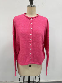 rose pink button-up cardigan on a mannequin in front of a white wall.