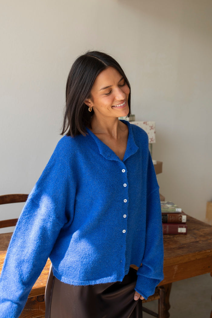royal blue button-up cardigan on a girl  in front of a desk.