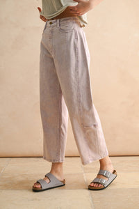 Person wearing light-colored jeans and sandals on a neutral background