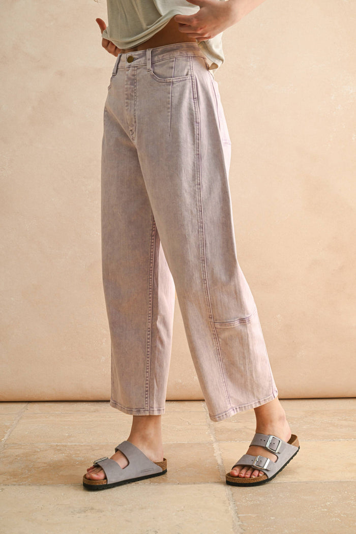 Person wearing light-colored jeans and sandals on a neutral background