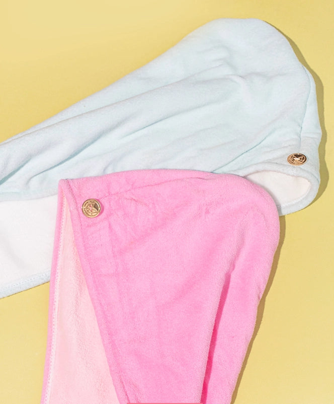 Two hair turbans, one white and one pink, on a yellow background.