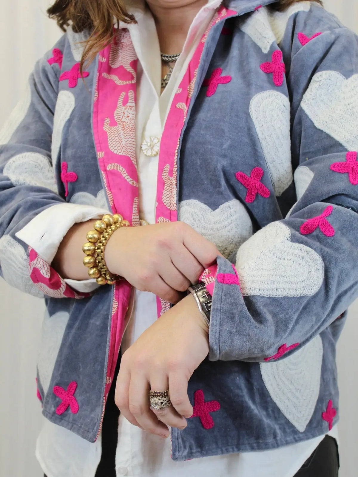 Person wearing a patterned jacket with pink and white designs on a plain background