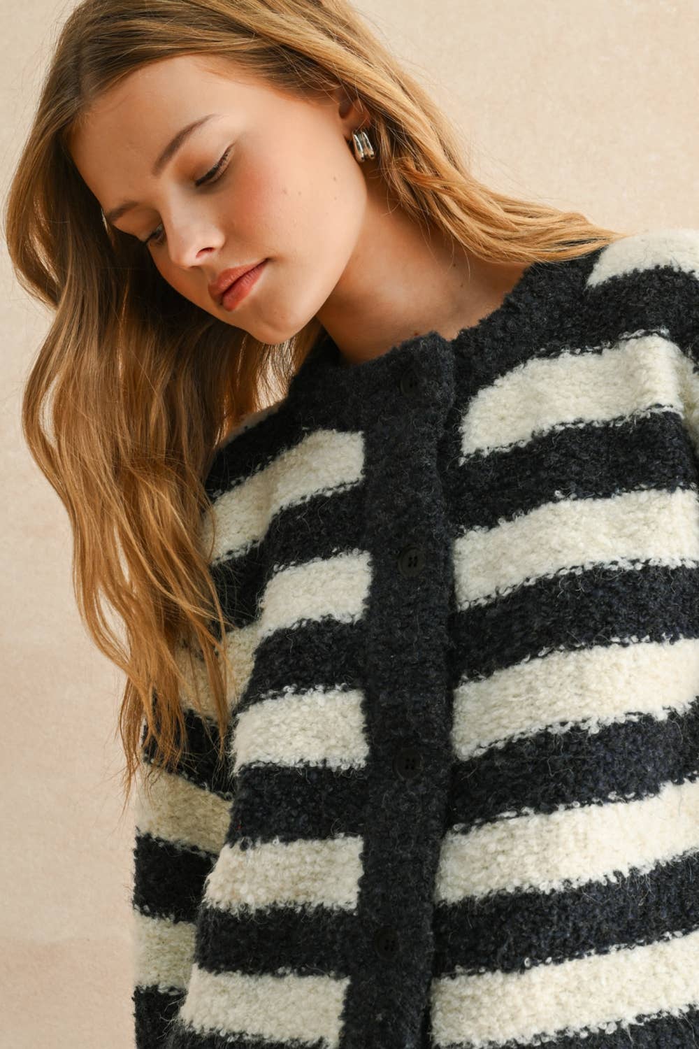 Woman wearing a black and white striped sweater against a beige background