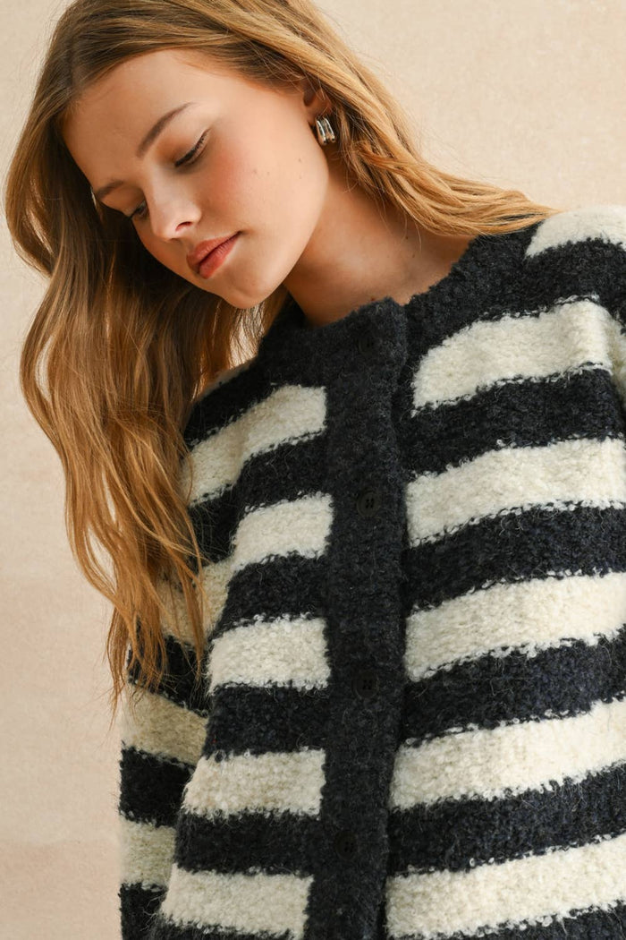 Woman wearing a black and white striped sweater against a beige background