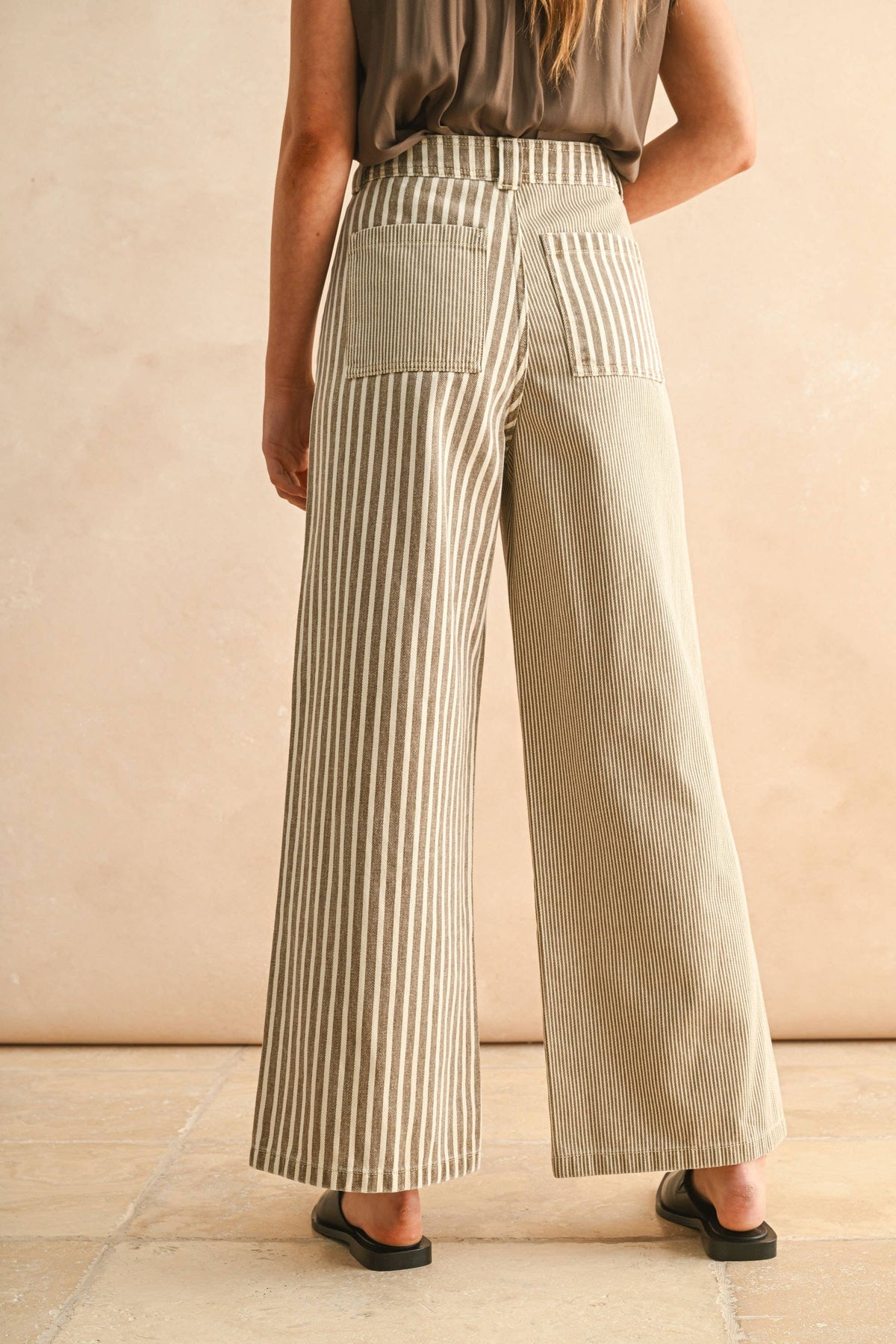 Person wearing beige striped wide-leg pants against a beige background