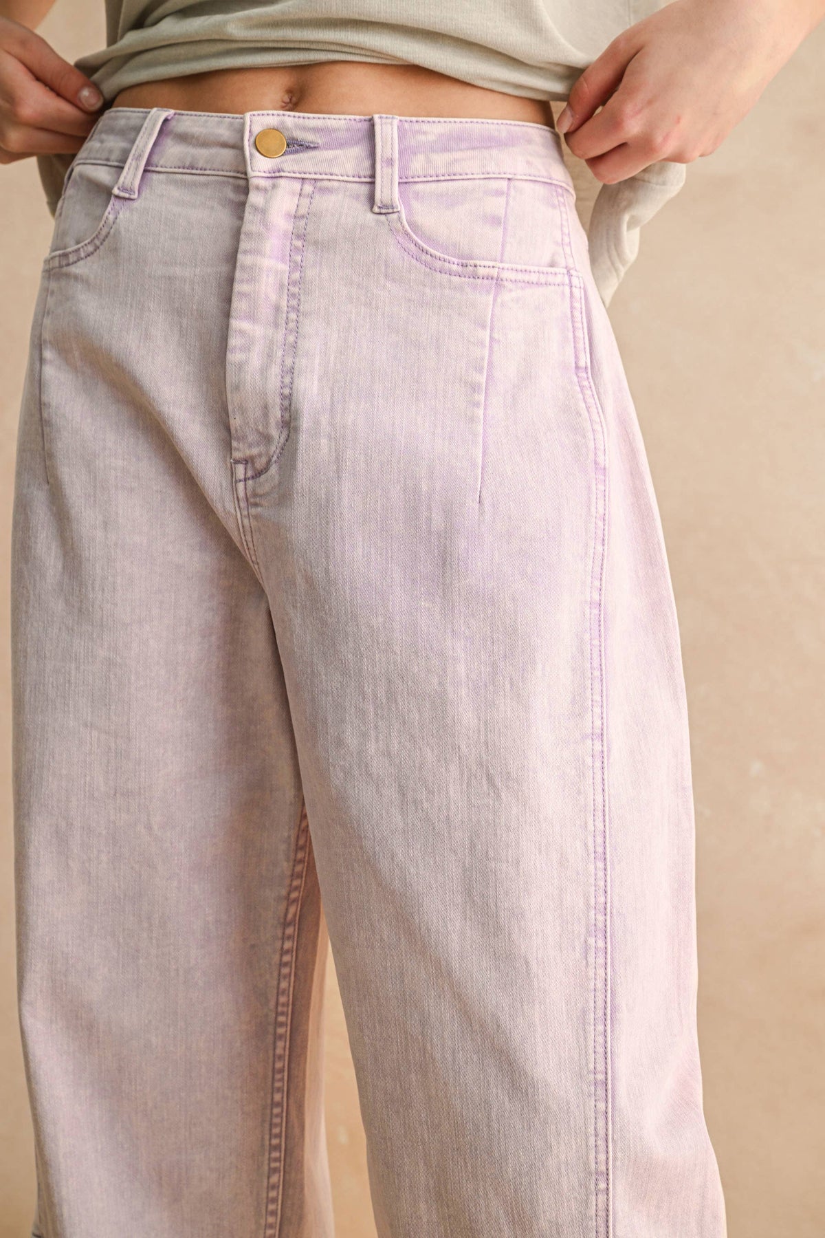 Light purple jeans worn by a person on a beige background