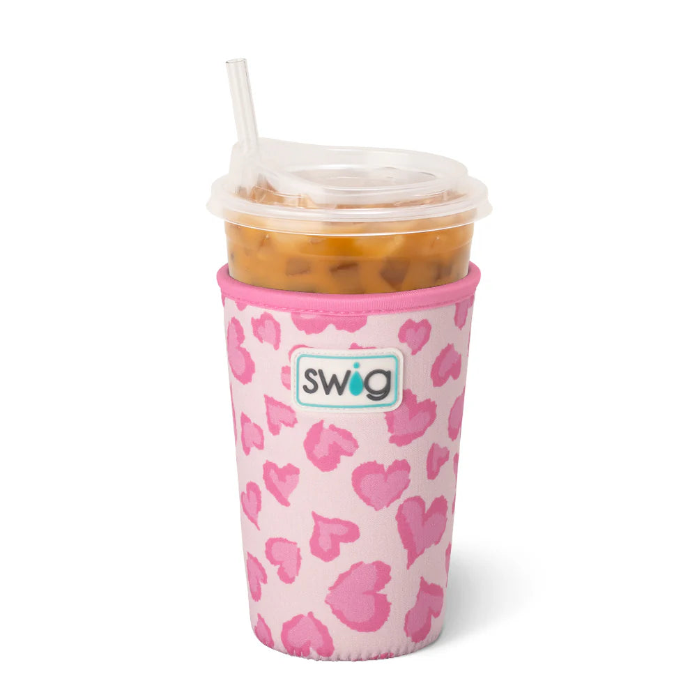 Pink heart-patterned insulated swig cup sleeve with iced coffee on a white background