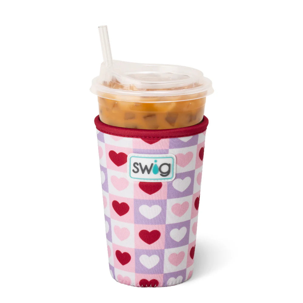 insulated swig cup coolie with heart pattern and holding an iced coffee cup with a straw on a white background