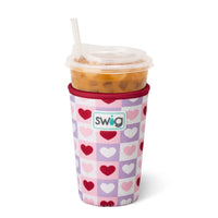 insulated swig cup coolie with heart pattern and holding an iced coffee cup with a straw on a white background