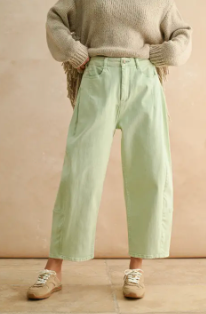 person wearing pastel mint colored denim pants in front of a beige background