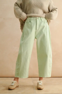 person wearing pastel mint colored denim pants in front of a beige background