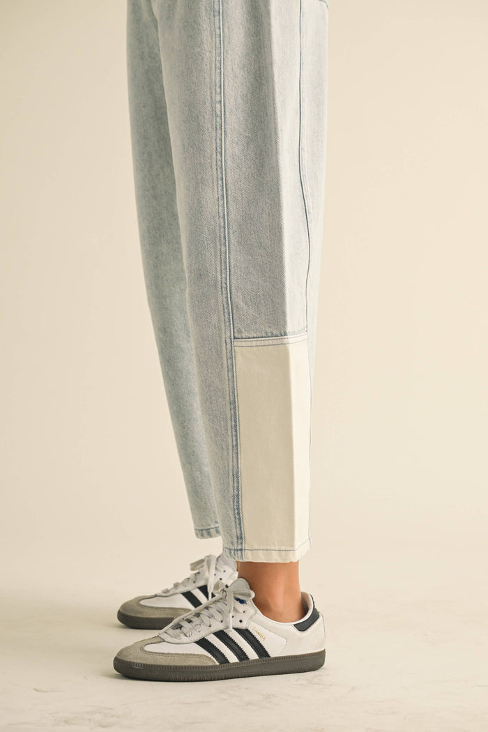 Person wearing light blue jeans and Adidas sneakers on a beige background