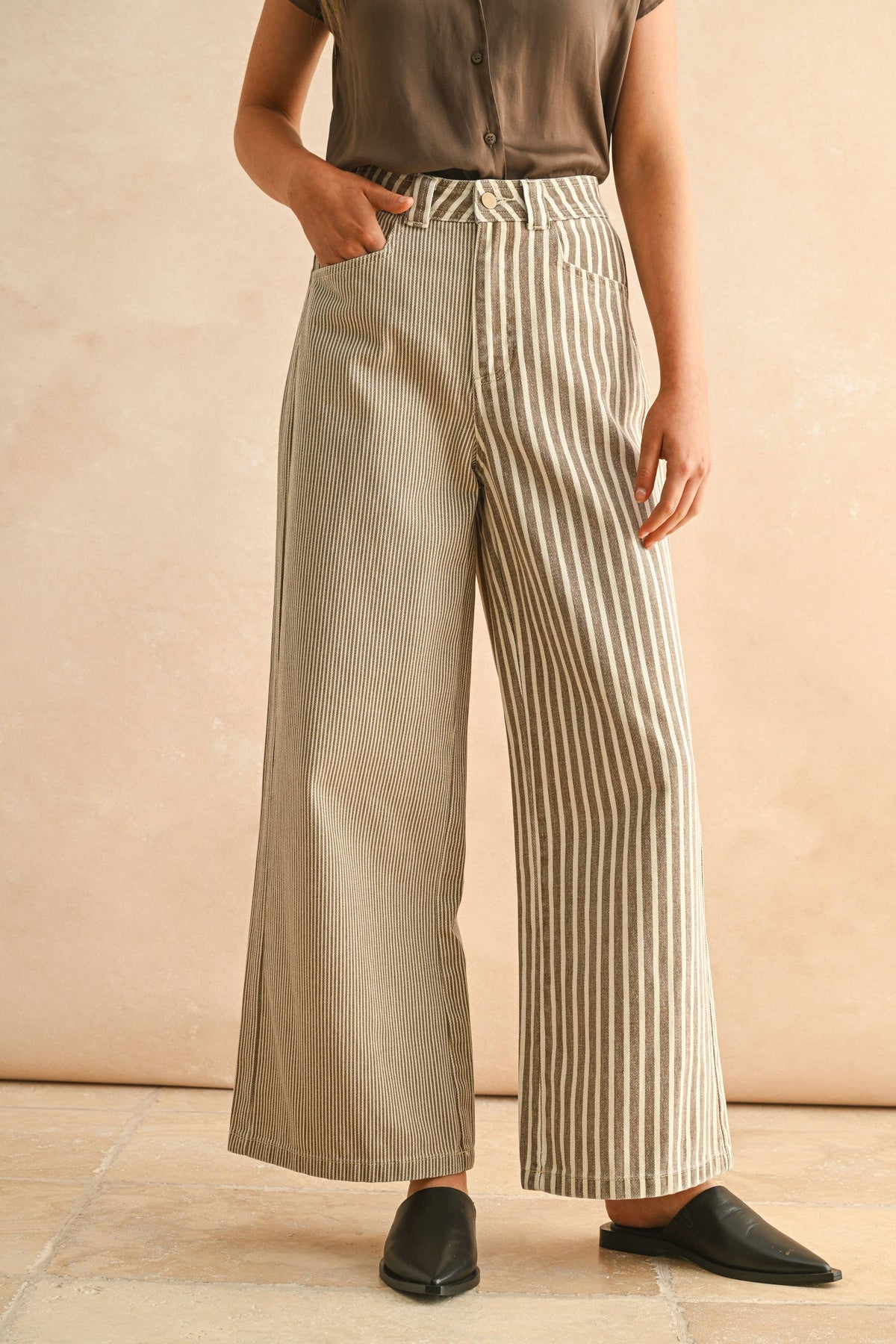 Person wearing beige wide-leg pants with white stripes against a beige background