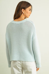 Woman wearing a light blue knitted sweater against a plain background