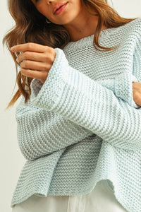 Person wearing a light blue knitted sweater against a neutral background
