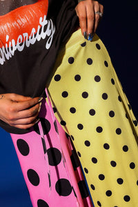 Person holding colorful polka dot fabrics with 'University' text on a black background